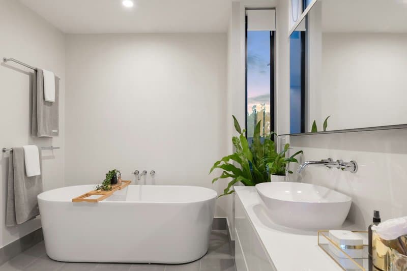 A freestanding tub and a vessel sink in a bright, minimalist bathroom
