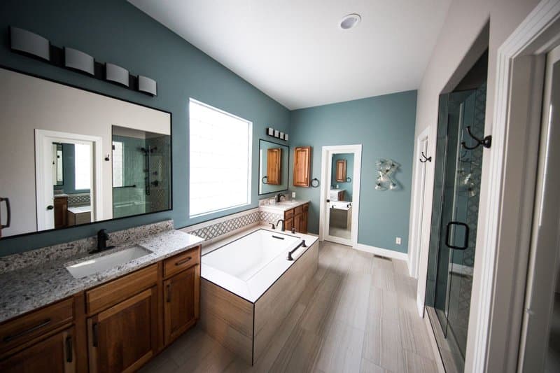A remodeled bathroom with a soaking tub, a wood vanity, and a granite counter