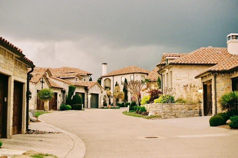 A row of stone homes with clay tile roofs along a quiet residential street