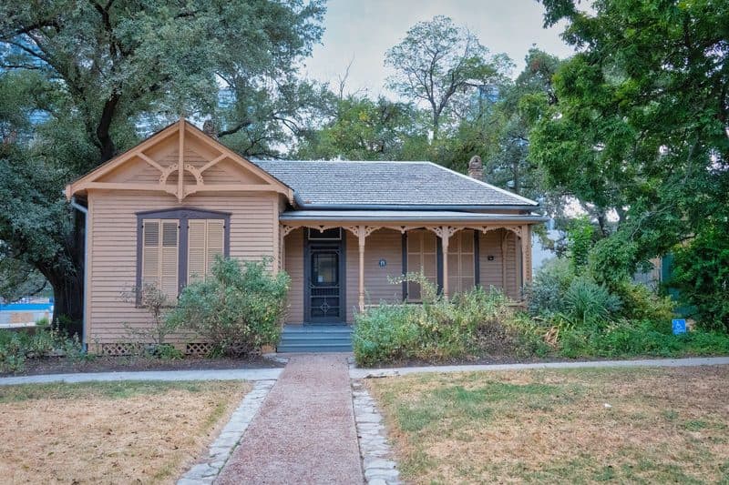 A historic wood-sided house in Austin with shuttered windows and a gingerbread porch