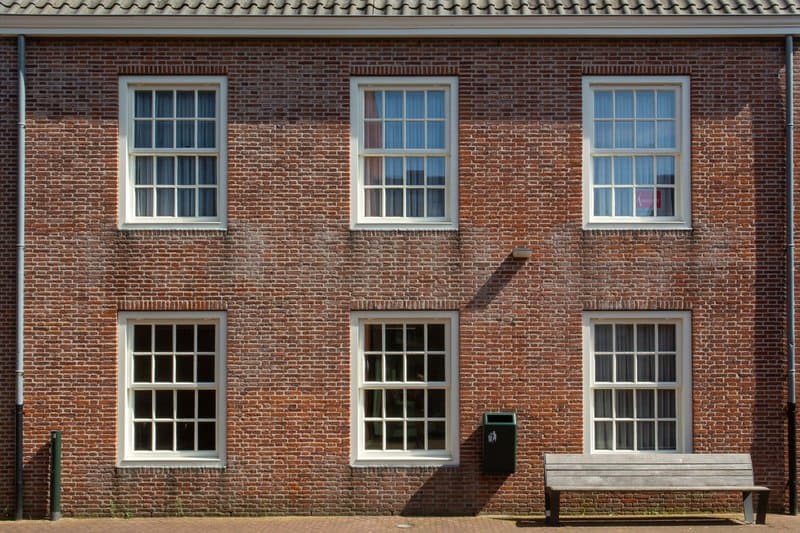 Two stories of white sash windows on a brick facade
