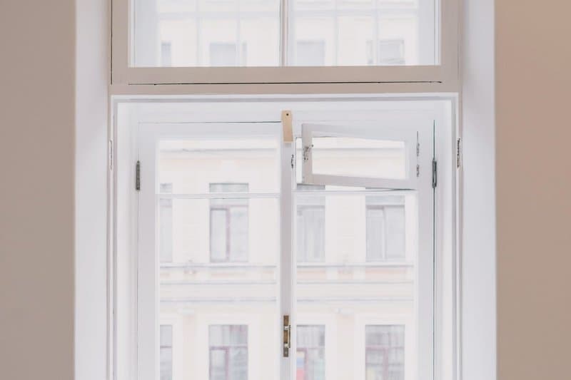 A newly installed white window swung open in a freshly painted room