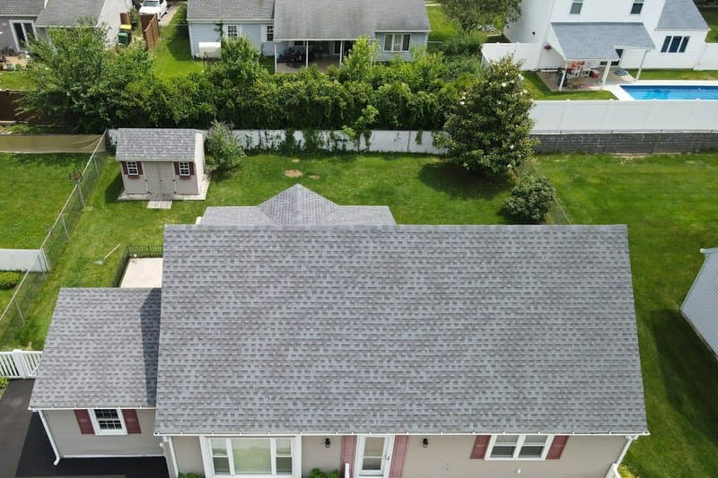Aerial view of a two-story suburban home with a new gray asphalt shingle roof